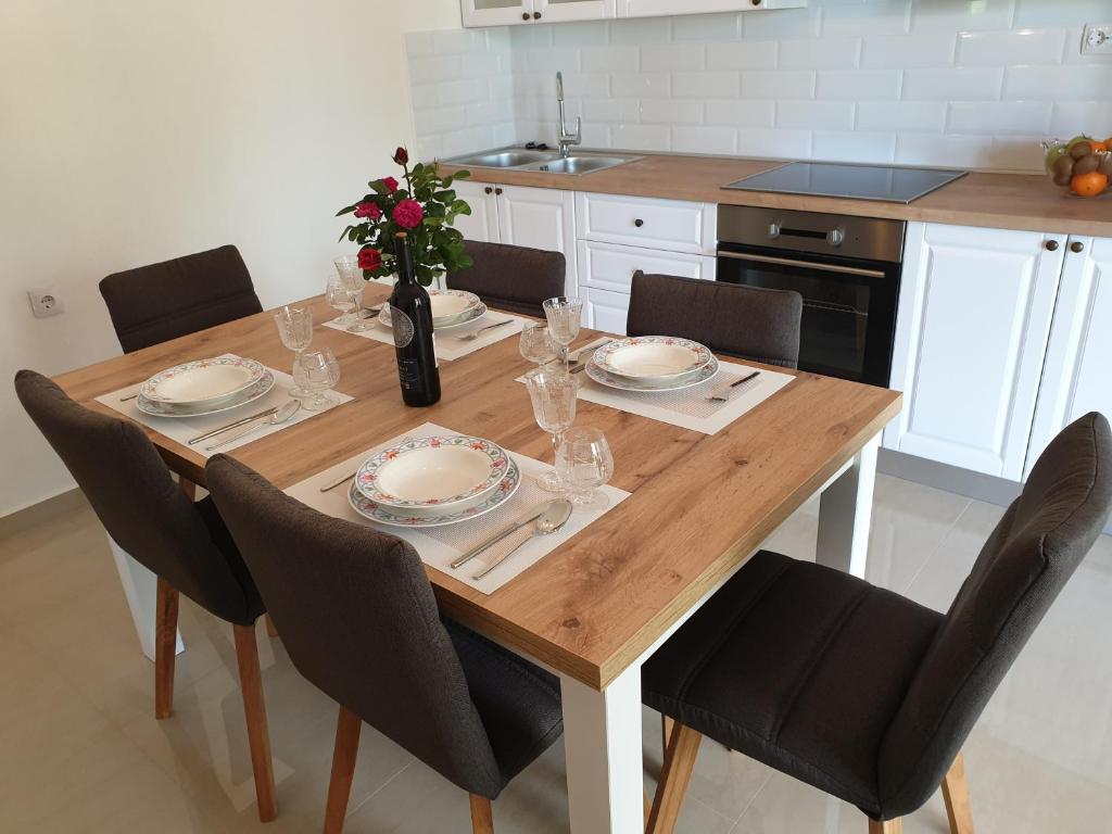a dining room table with chairs and a table with plates and glasses at Apartment Kristina in Vlašići