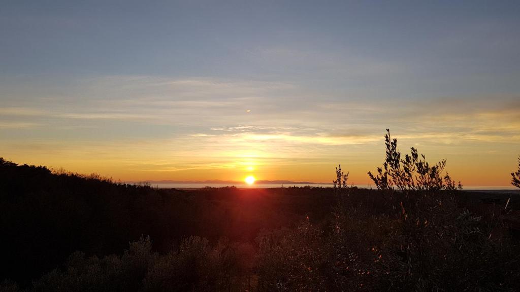 una puesta de sol con la puesta de sol en la distancia en Il Panorama en Montescudaio