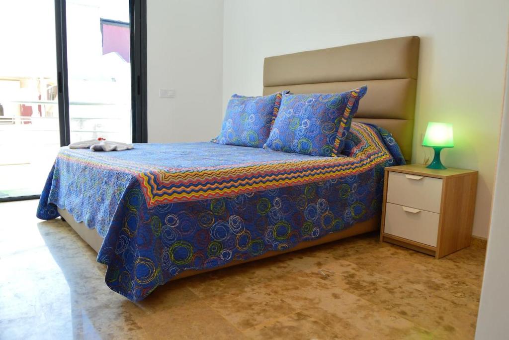 a bed with a blue comforter and a lamp on a table at Beau studio à Rabat calme et sécurisé in Rabat