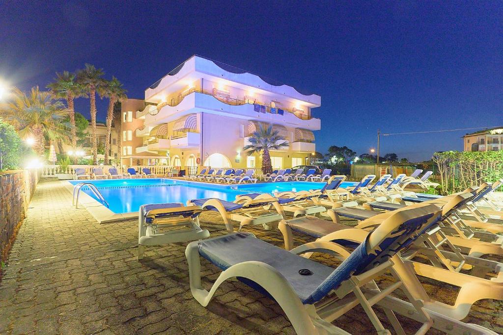 a group of lounge chairs next to a swimming pool at Hotel Rivadoro-Spiaggia ombrellone e lettini inclusi-Piscina-Parcheggio in Martinsicuro