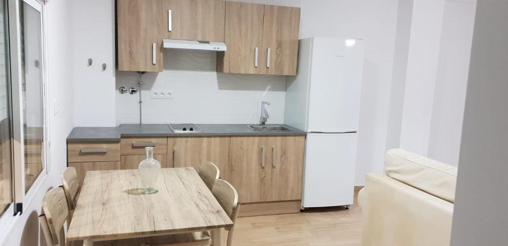 a kitchen with a wooden table and a white refrigerator at Apartamento NUEVO JEREZ BAHIA in Jerez de la Frontera