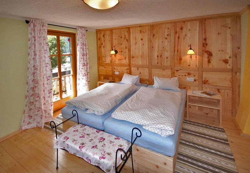 ein Schlafzimmer mit einem blauen Bett in einem Zimmer mit Holzwänden in der Unterkunft Gasthof Dorfschenke in Stall