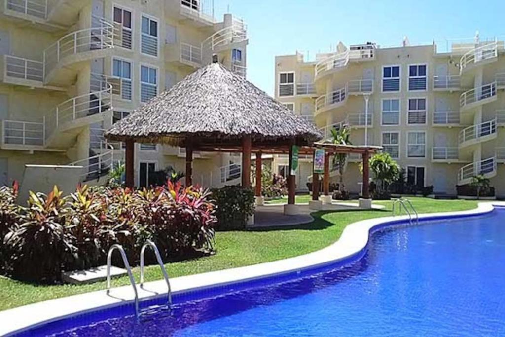 a swimming pool with a gazebo next to a building at Depa Marina Diamante · Depto PB internet Alberca Palapa Acapulco Marina Diamante in Acapulco