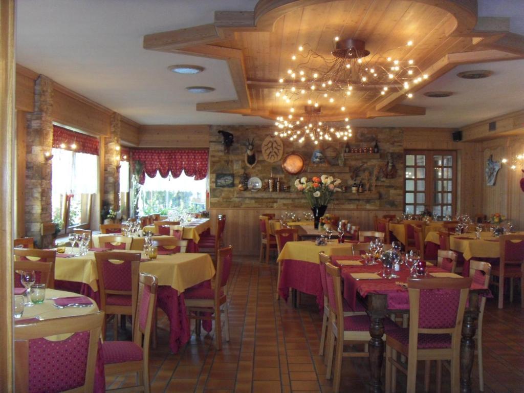 restauracja ze stołami i krzesłami oraz żyrandolem w obiekcie Hotel Corona w mieście Branzi