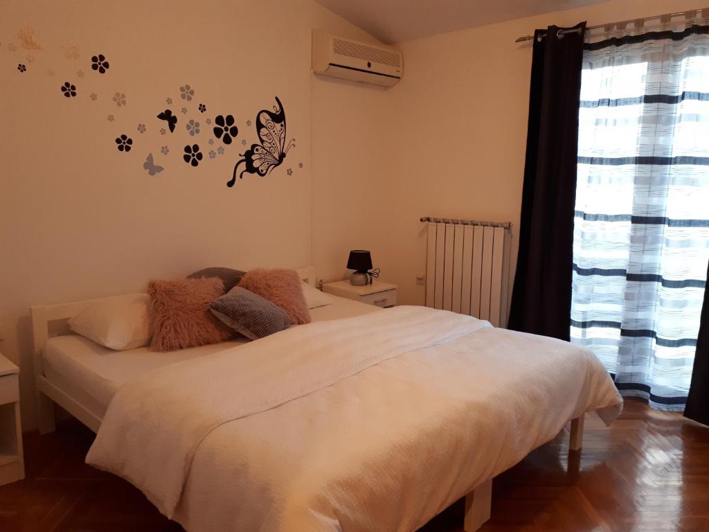1 dormitorio con 1 cama con sábanas blancas y mariposas en la pared en Apartments Sara, en Tisno