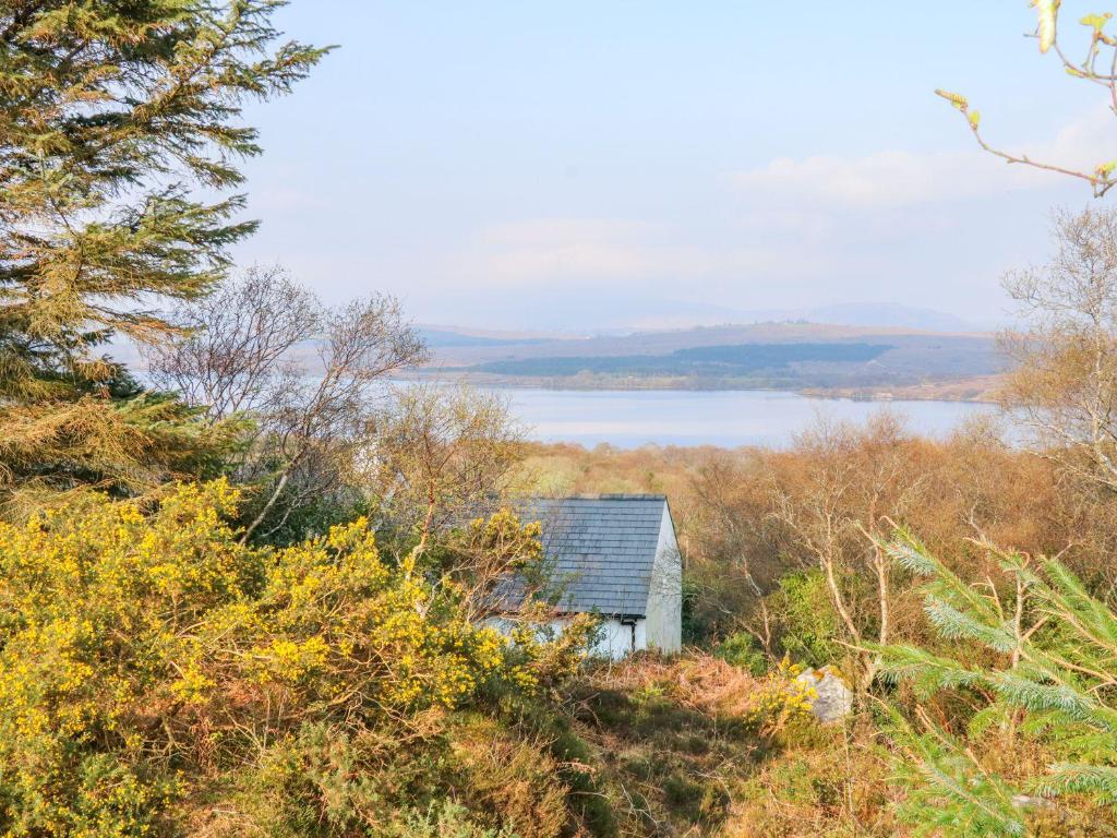 an old house on the side of a hill with a lake at Lough View Cottage in Carrigart