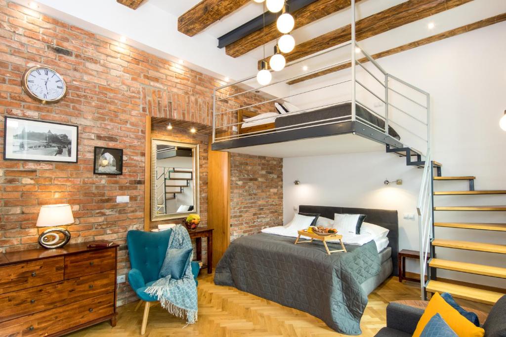 a bedroom with a bed and a brick wall at Cracowapart Loft Gertruda in Kraków