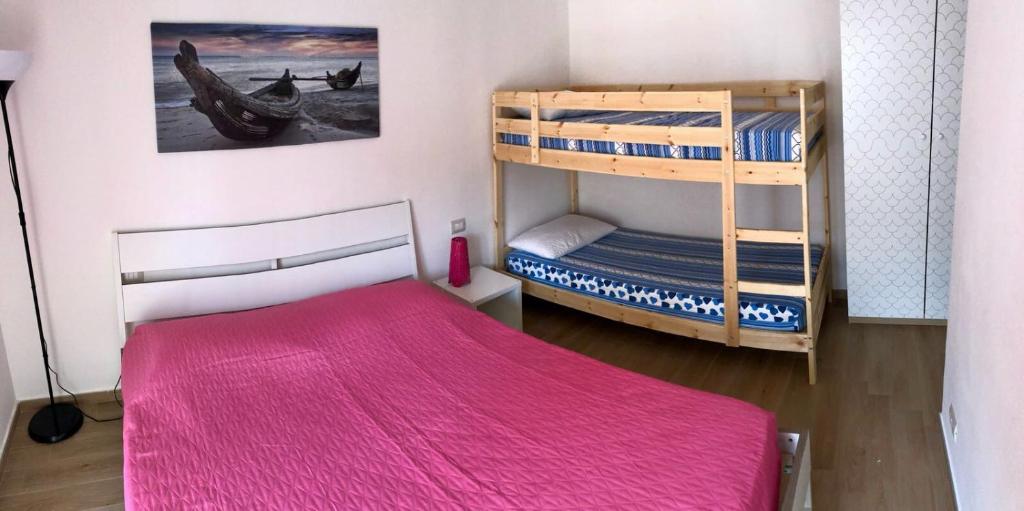 um quarto com 2 beliches e um cobertor rosa em Rose Beach Apartment em Margherita di Savoia