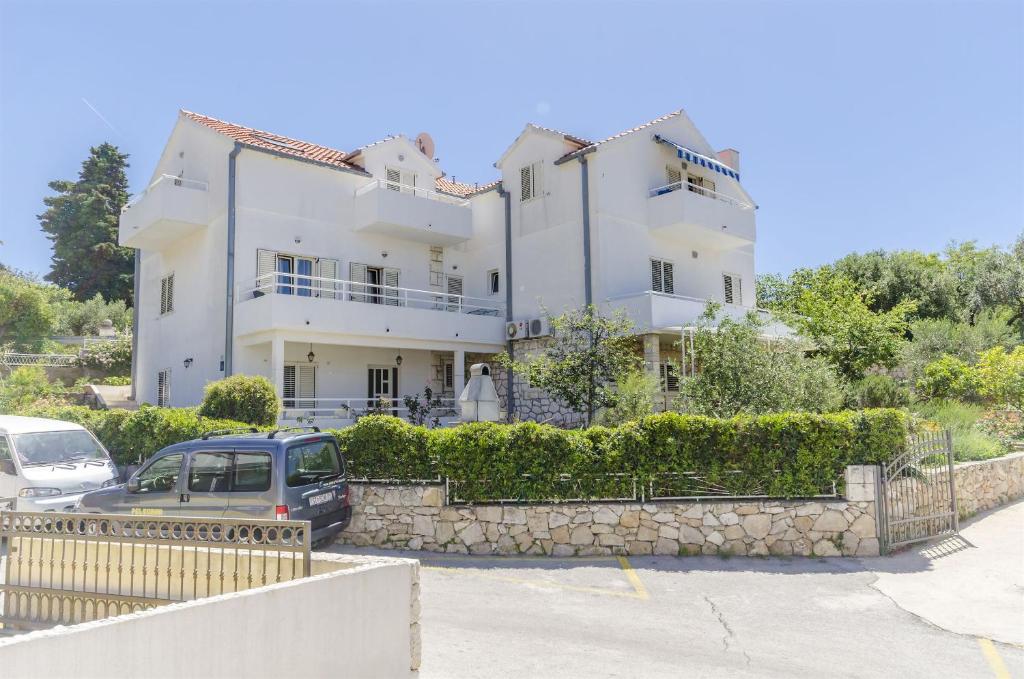 a large white house with cars parked in front of it at Apartments Jacky in Hvar