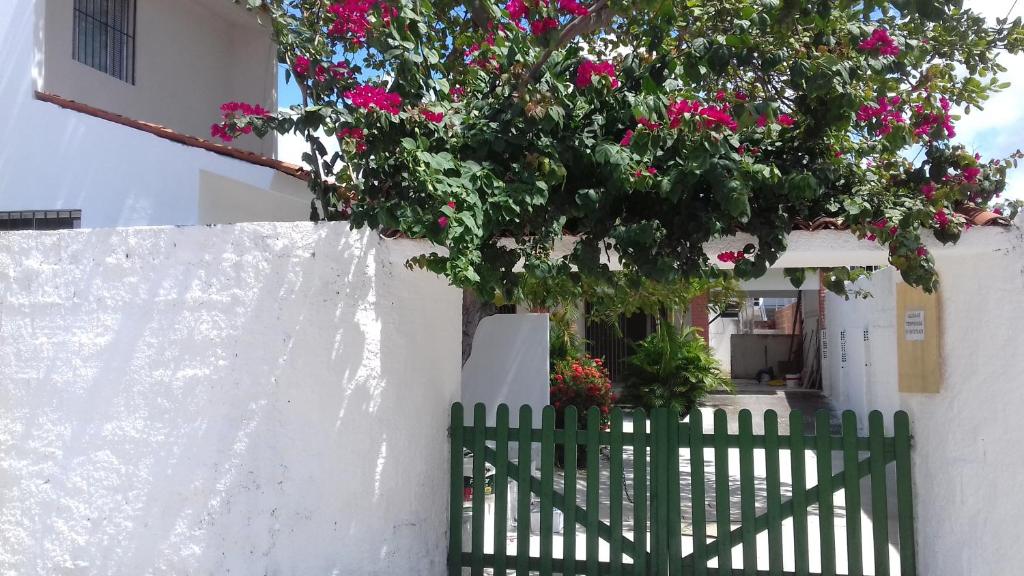 une clôture blanche avec des fleurs roses sur un bâtiment dans l'établissement Casa da Árvore, à Porto de Galinhas