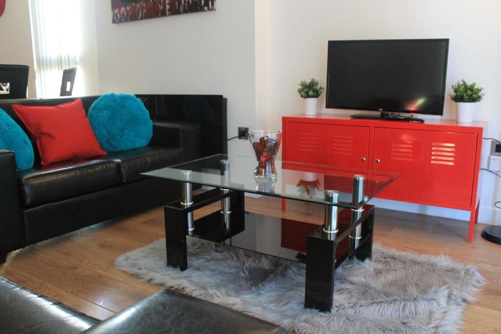 a living room with a glass coffee table and a television at Snapos Apartments - Blonk Street in Sheffield