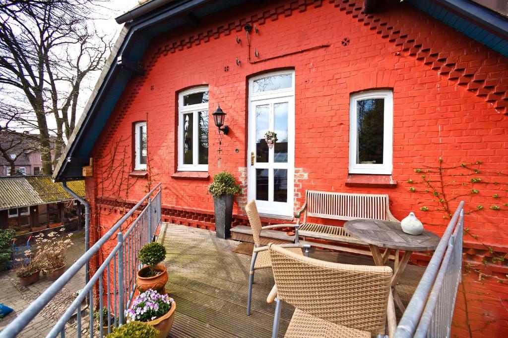 a red brick house with a table and chairs on a deck at Ferienhaus Eichhof, Garlstorf - Lüneburger Heide in Garlstorf