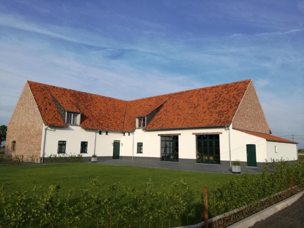 un grand bâtiment blanc avec un toit orange dans l'établissement B&B Allegambe's Goed, à Zedelgem