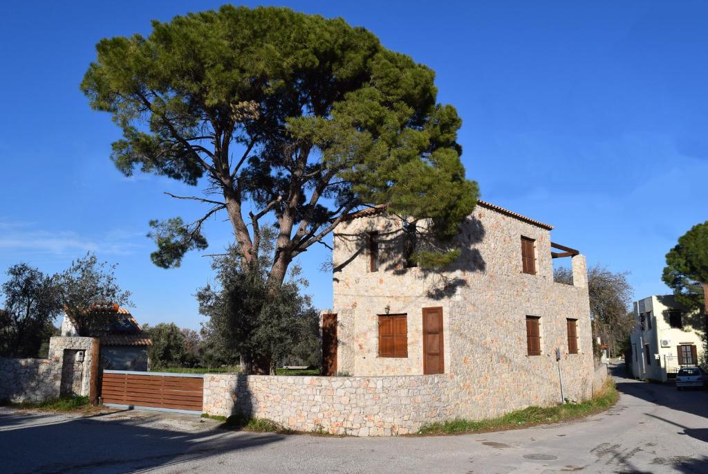 un viejo edificio de piedra con un árbol detrás. en Pyrgos Luxury Country Home, en Ialisos