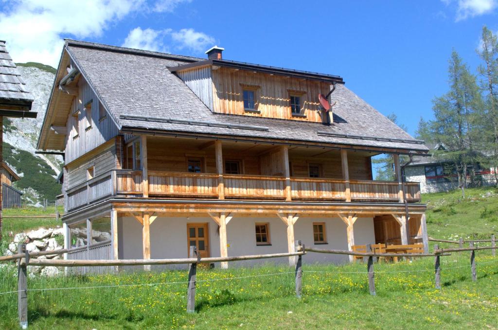 a large wooden house with a balcony on a hill at Lärchenhütte in Tauplitzalm