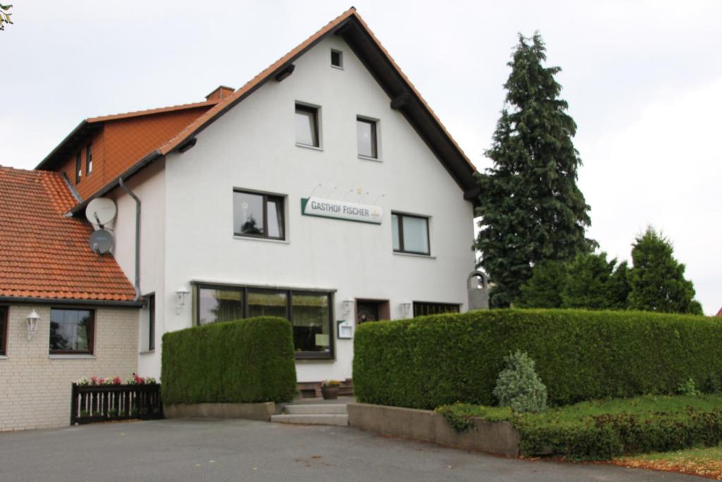 Ein weißes Gebäude mit einem Schild drauf. in der Unterkunft Pension Fischer in Bad Driburg