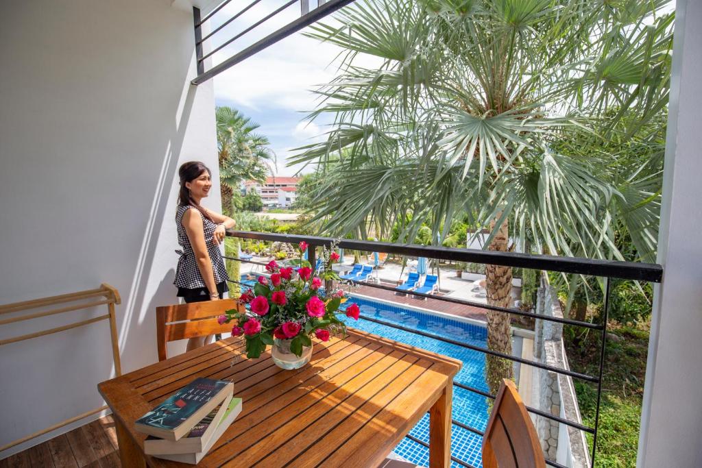 a woman standing on a balcony with a table and flowers at Sungthong Kamala Beach Resort in Kamala Beach
