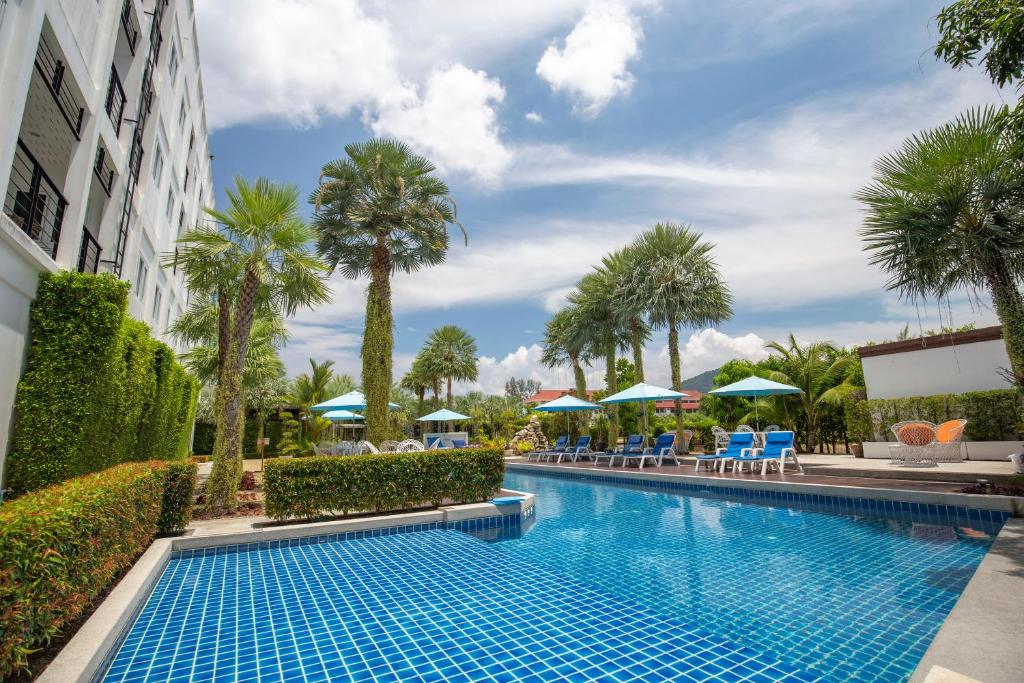 a pool at a hotel with palm trees and umbrellas at Sungthong Kamala Beach Resort in Kamala Beach