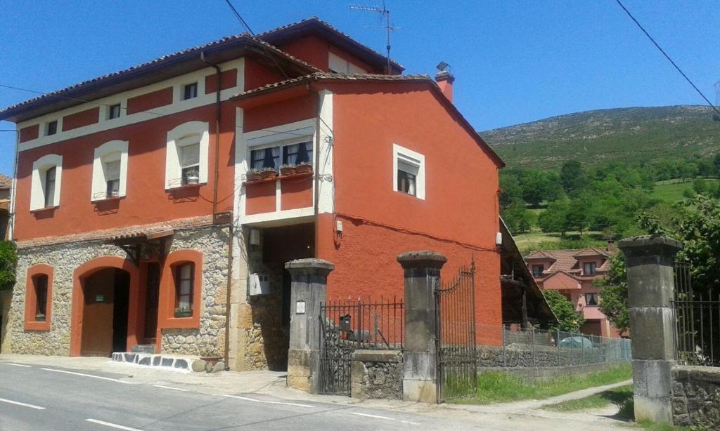 ein rotes Haus mit einem Zaun davor in der Unterkunft Miyares casa rural in Miyares