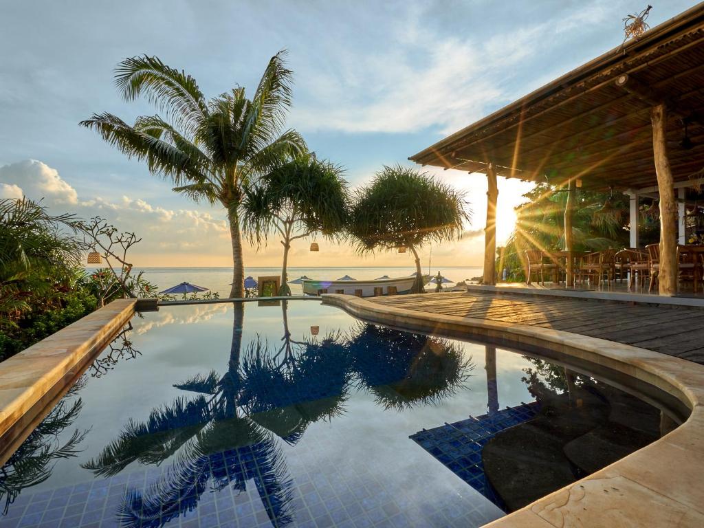 a swimming pool in front of a house with the ocean at Vienna Beach Resort in Amed