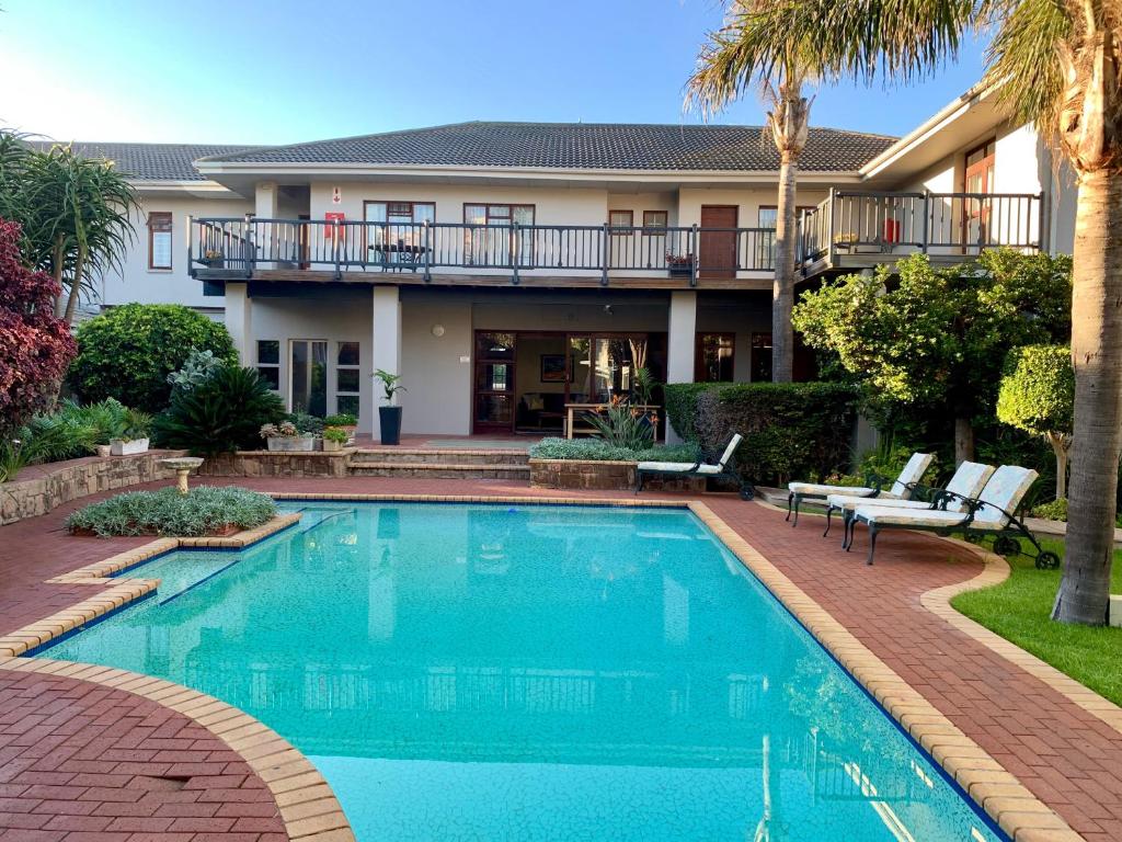 a swimming pool in front of a house at Fifth Avenue Beach House in Port Elizabeth