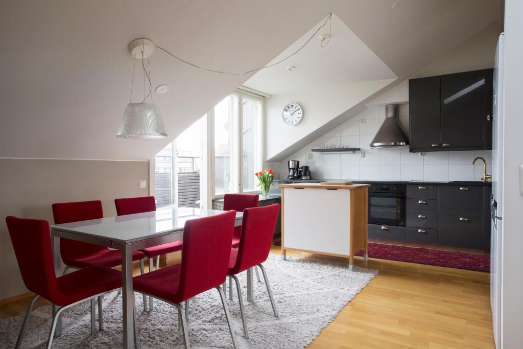 cocina y comedor con mesa y sillas rojas en 2ndhomes 2BR City Center Penthouse with Balcony and Sauna, en Helsinki