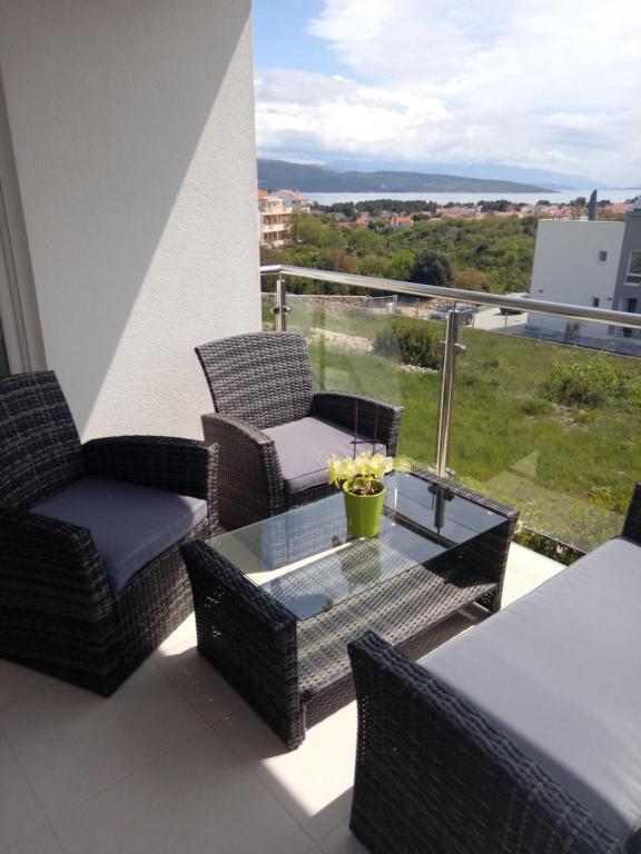 een balkon met rieten stoelen en een glazen tafel bij Apartment Nena in Krk