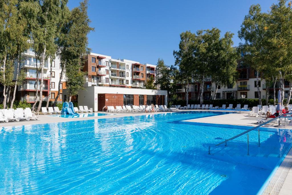 a large swimming pool with chairs and buildings at Apartamenty Osiedle Polanki by Renters in Kołobrzeg