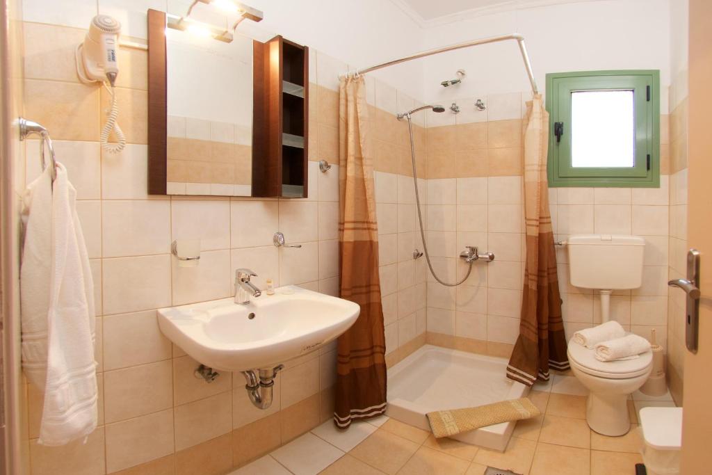 a bathroom with a sink and a shower and a toilet at Minas Apartments in Divarata