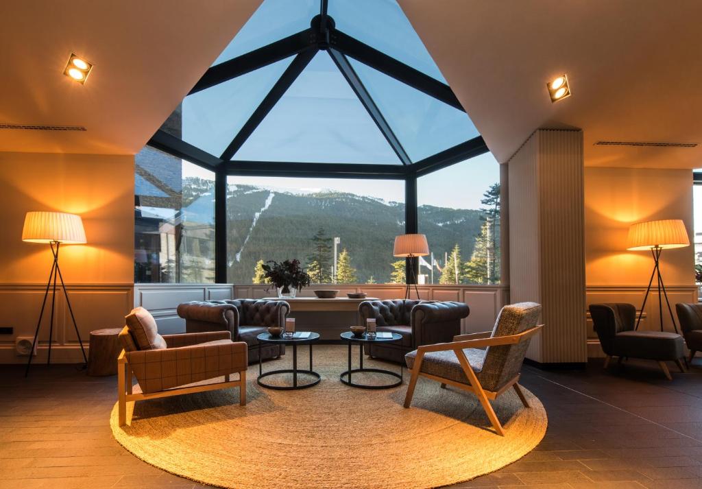 ソルデュにあるPark Piolets MountainHotel & Spaのリビングルーム(大きな窓、椅子、テーブル付)