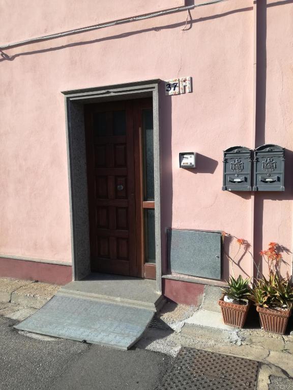 a pink building with a door and two plants at Casa Vacanza Dante in Nurachi