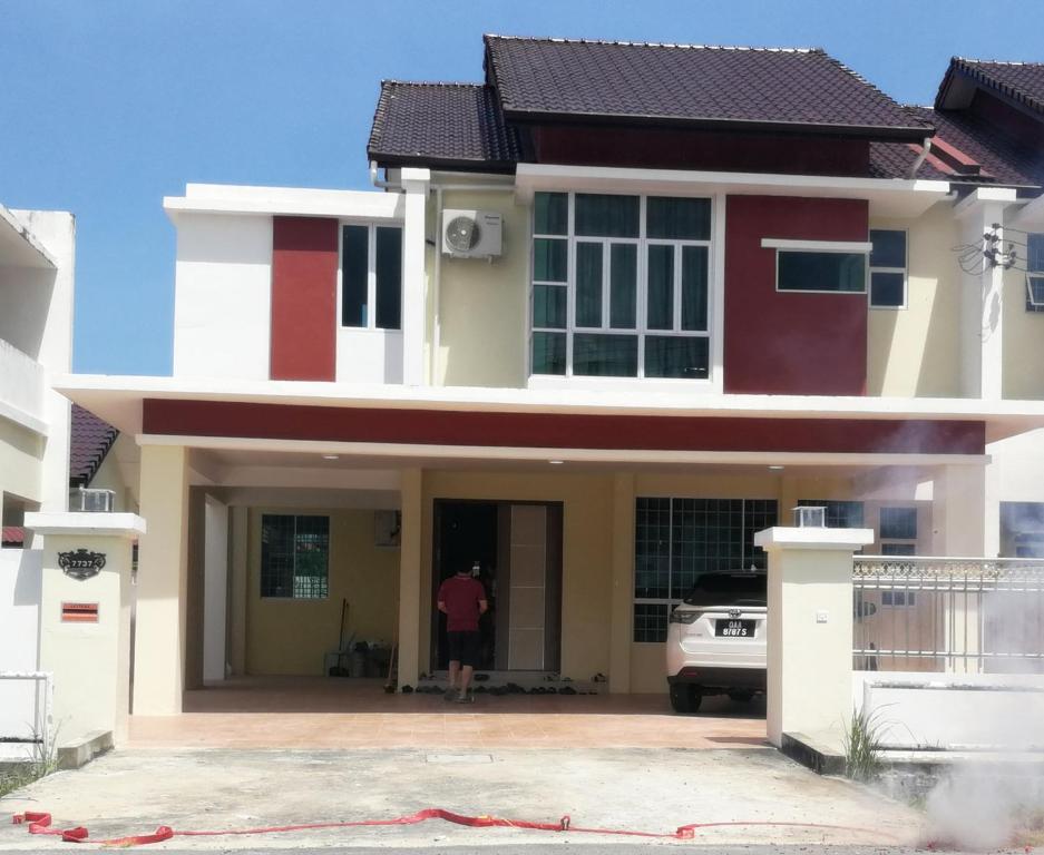 a man standing in the doorway of a house at HomezStay Airport Miri in Miri