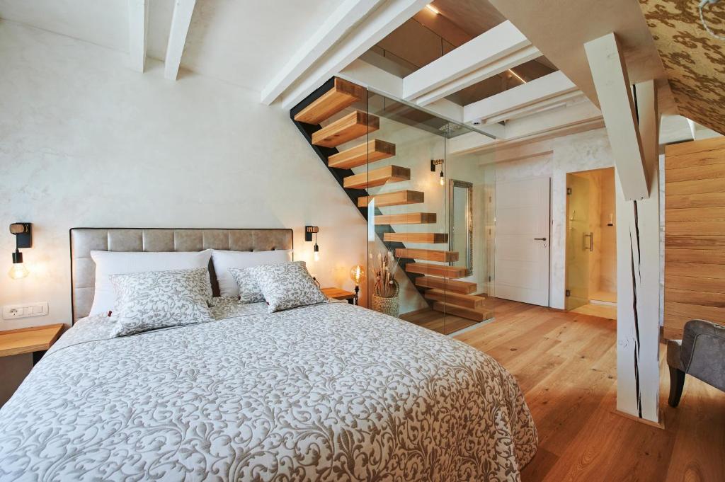 a bedroom with a large bed and a staircase at Hiša Ančka, Boutique Hotel & Maja Rooms in Slovenj Gradec