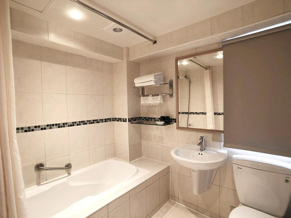 a bathroom with a sink and a tub and a toilet at Shihzuwan Hotel – Kaohsiung Station in Kaohsiung