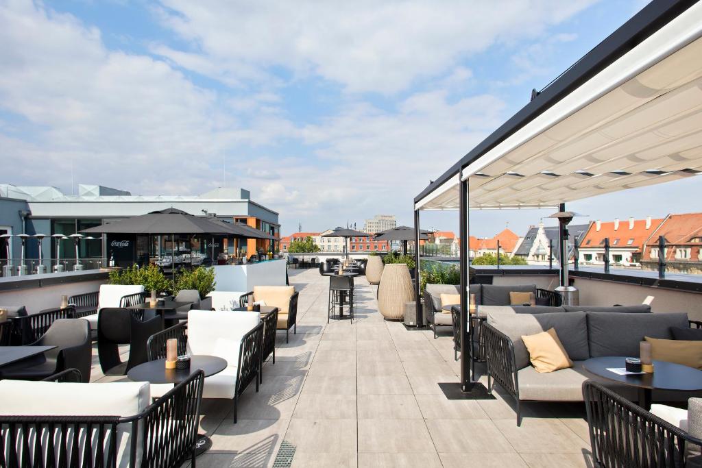 a patio with couches and tables on a roof at INNSiDE by Meliá Leipzig in Leipzig