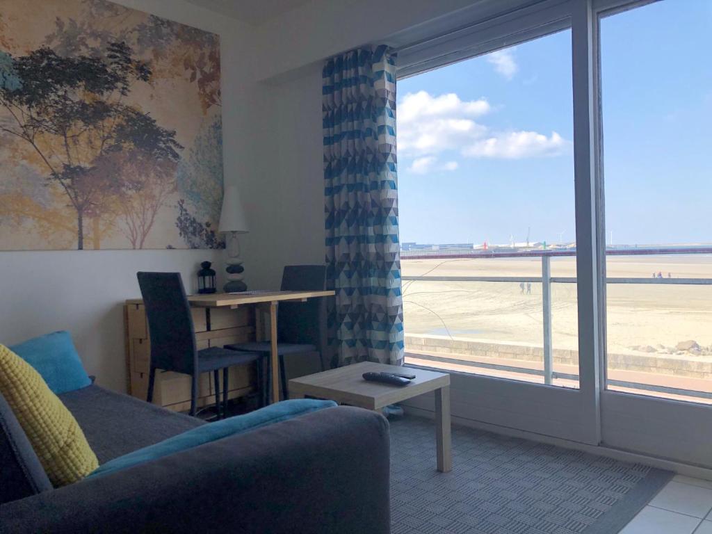 - un salon avec un canapé et une vue sur l'aéroport dans l'établissement Brise Lame Face Mer, à Boulogne-sur-Mer