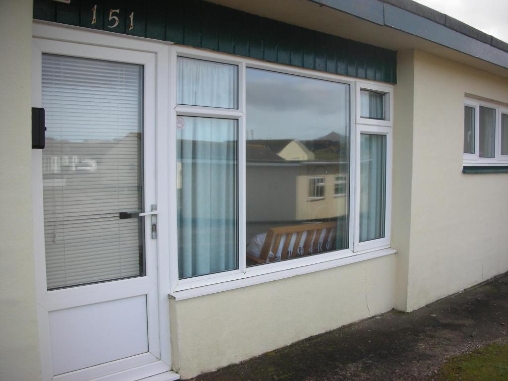 a house with a door and a window with a bench at 151 Perran Sands in Perranporth