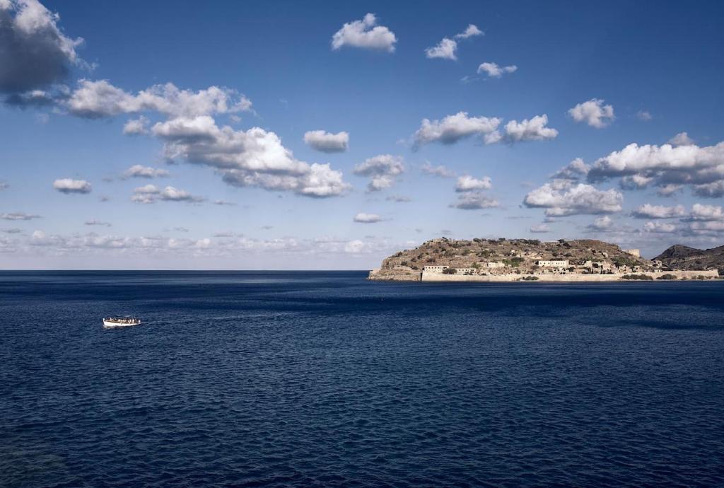 a boat in the water with an island in the distance at Plaka Sea Front Residence in Elounda