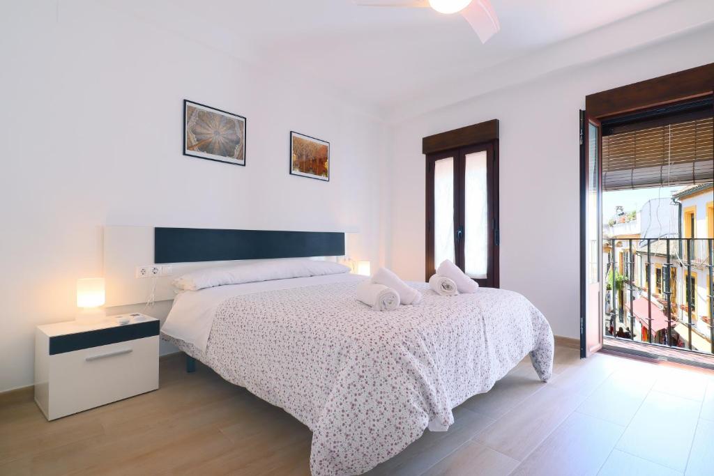 a white bedroom with a bed and a window at Rosas en la Balconada & Apartment with Parking in Córdoba Historic Center in Córdoba