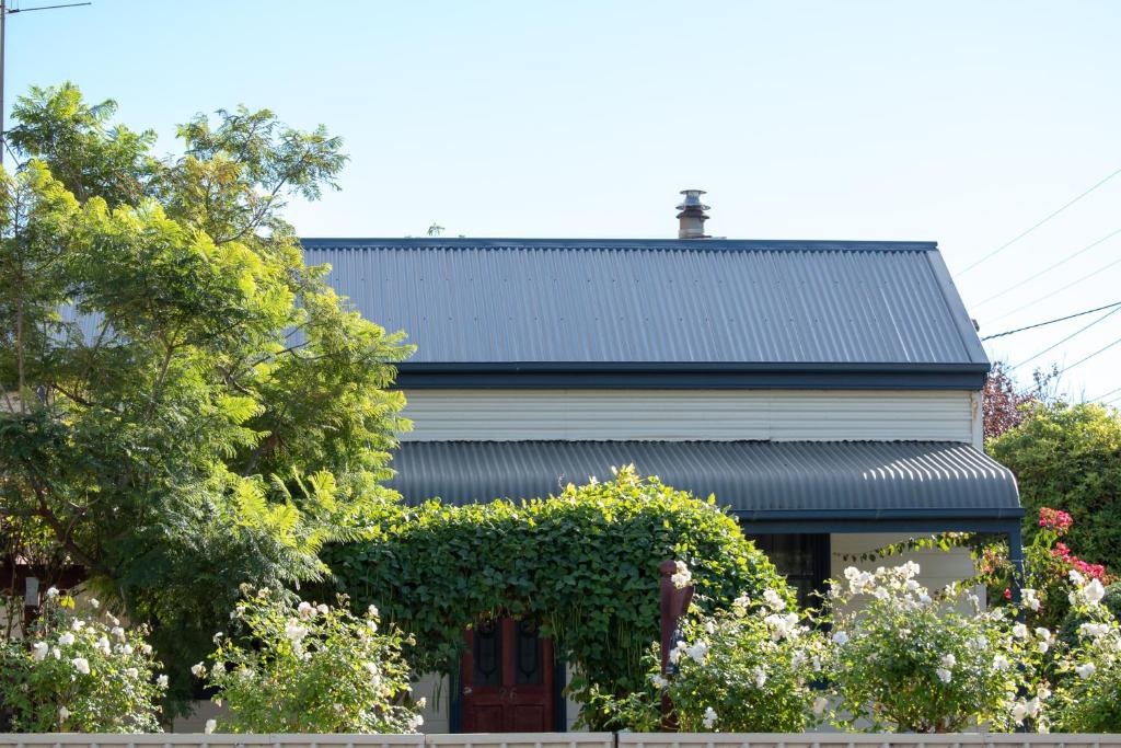 a house with a blue tin roof and flowers at Haven Cottage Kangaroo Island in Kingscote