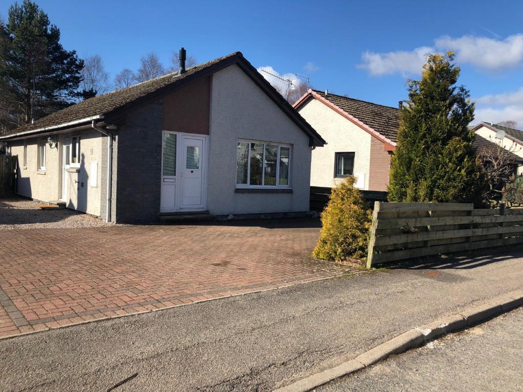 uma casa com uma entrada de tijolos em frente em Linmore em Aviemore