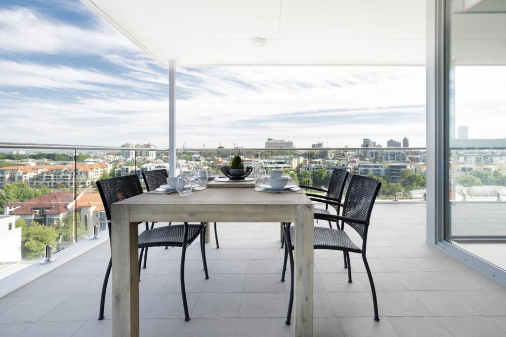y balcón con mesa de comedor y sillas. en Minimalist Penthouse Condo with Skyline Vistas, en Perth