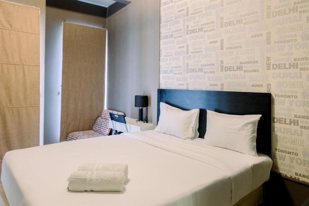a bedroom with a large white bed and a wall at Comfy Studio Apartment @ Skylounge Tamansari By Travelio in Tangerang