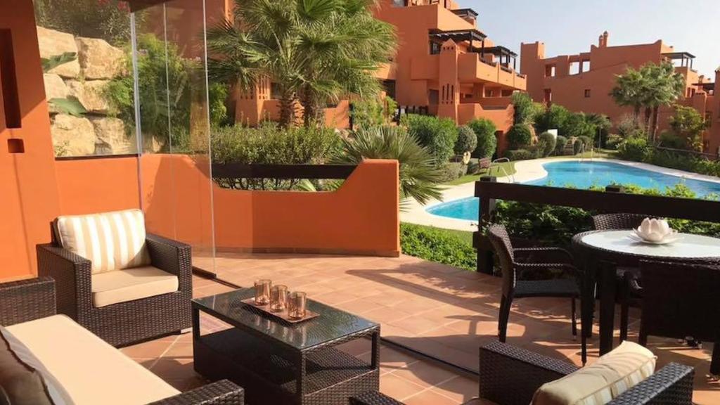 une terrasse avec des chaises, une table et une piscine dans l'établissement Beautiful apartment in Costa del Sol,300m from sea, à Estepona