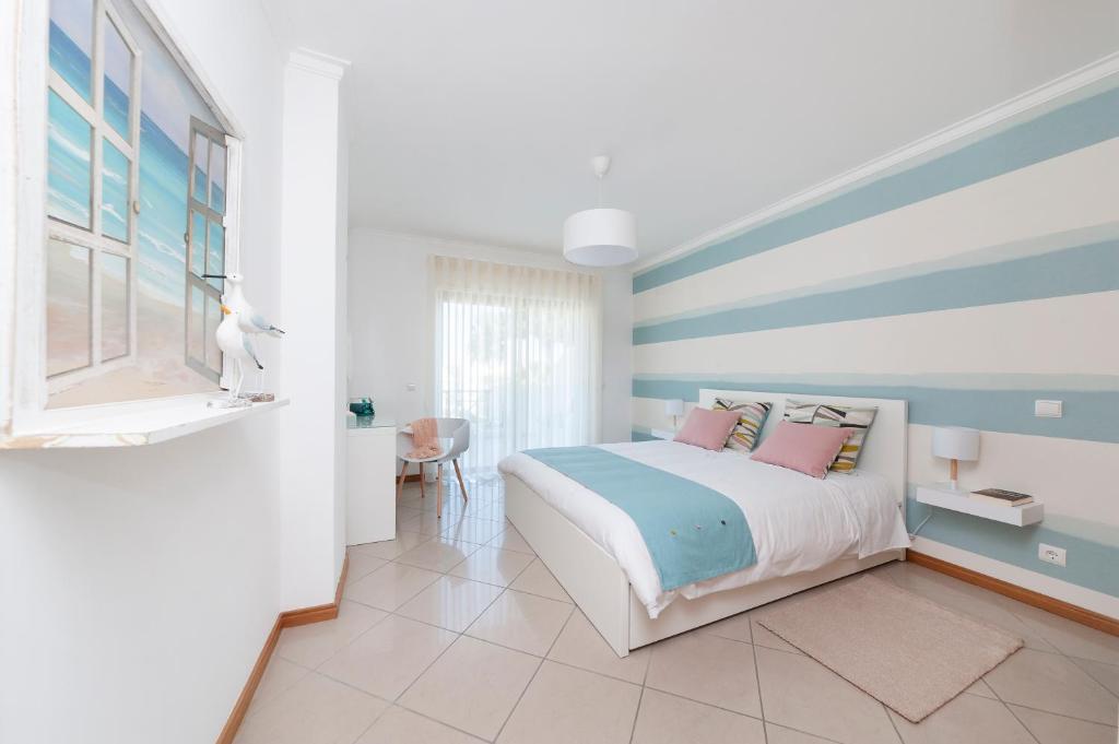 sypialnia z łóżkiem z niebieskimi i białymi paskami w obiekcie Santa Eulalia BlueSea Apartment w Albufeirze