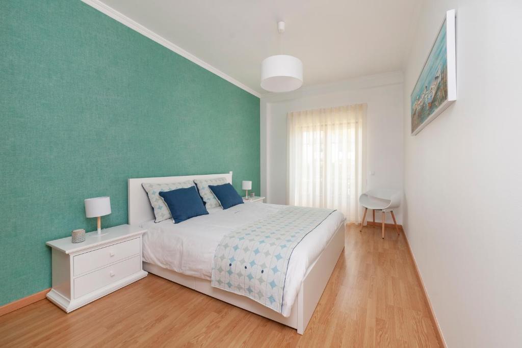 um quarto com uma cama branca e uma parede verde em Oura BlueSea Apartment em Albufeira