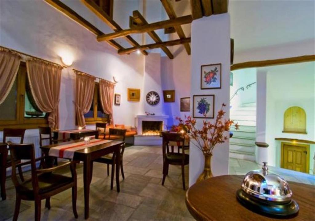 a living room with a table and chairs and a fireplace at Alkifron Hotel in Kala Nera