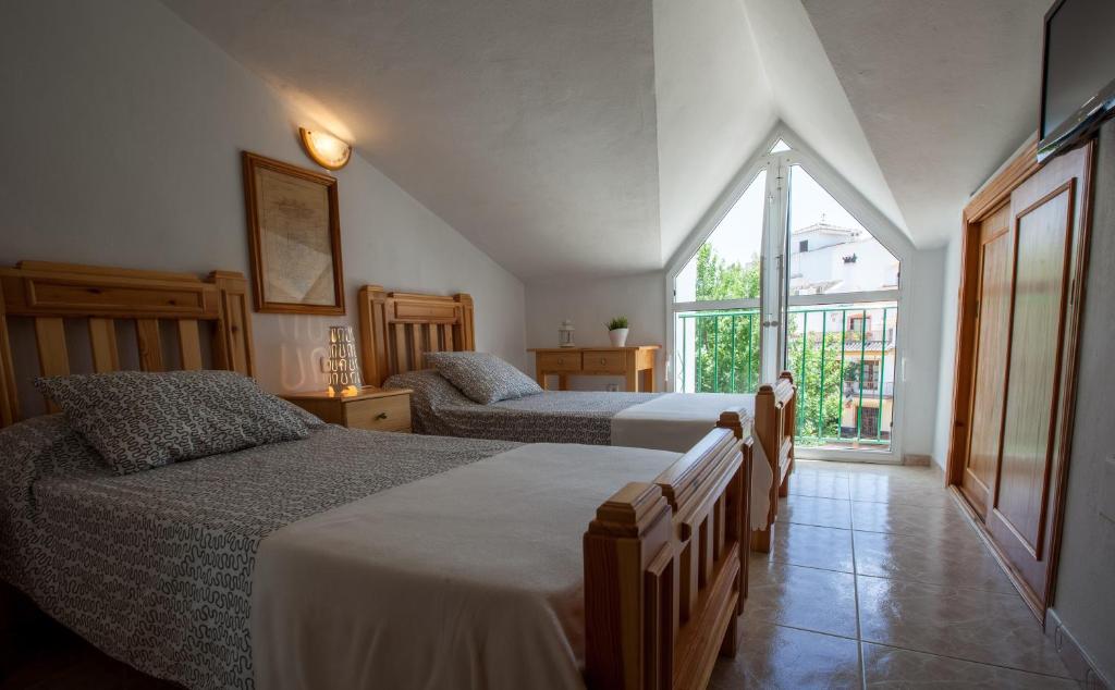 a bedroom with two beds and a large window at Hostal Sango Sierra de las Nieves in Alozaina