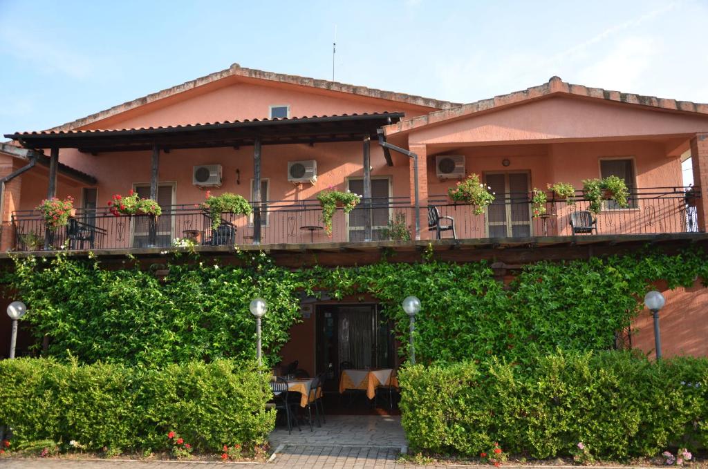 a house with a balcony with plants at Hotel La Mimosa in Capalbio