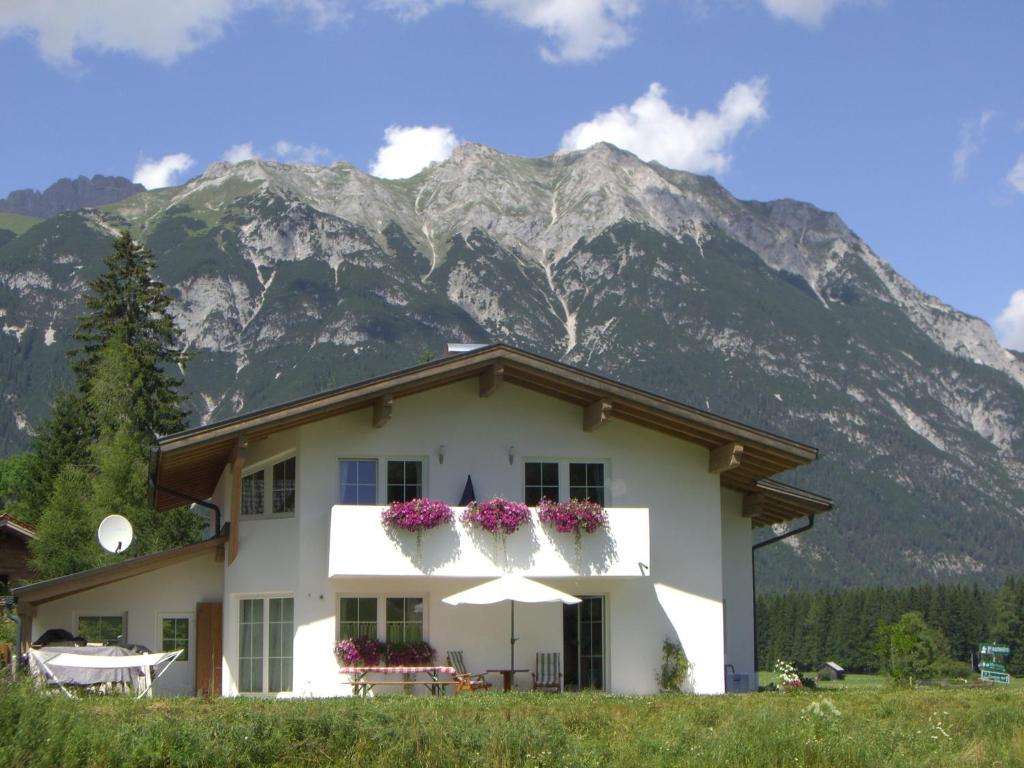 una casa bianca con fiori di fronte a una montagna di Landhaus Bellamontes a Leutasch